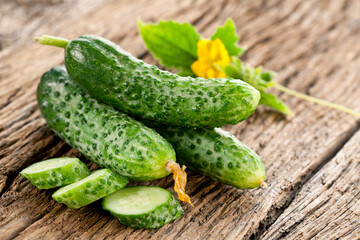 Cucumbers with green cucumber leaf on old rural wooden table.