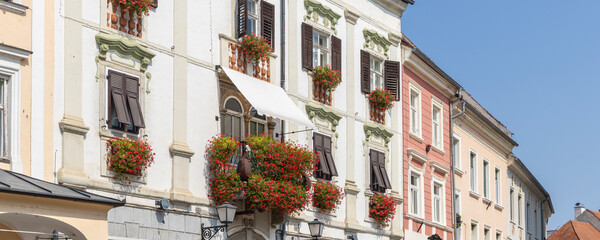 Ancient houses witrh flowers basket at square in front of the city tower of Ptuj along the Drava river in Styria region in Slovenia