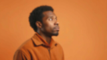 A reflective person immersed in thought, set against a blurred background and bold orange backdrop, perfect for conceptual projects