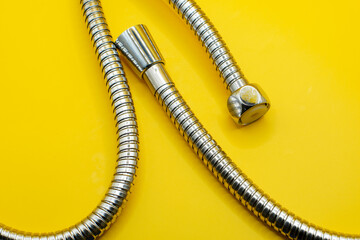 Chrome plated shower pipe, isolated on yellow background