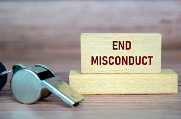 End Misconduct text on wooden blocks with whistle background. Whistleblow concept