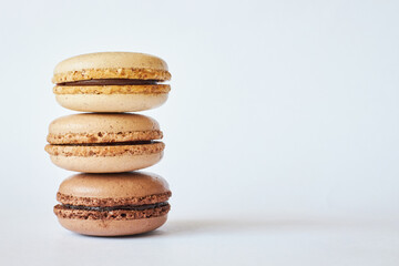 Stack of three brown French Macarons, cakes with different flavors, coffee and creme brulee flavor. pyramid of homemade dessert, macaroons side view, Copy space for text