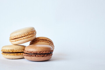 Four brown French Macarons, cakes with different flavors, coffee and creme brulee flavor. pyramid of homemade dessert, macaroons side view, Copy space for text, closeup