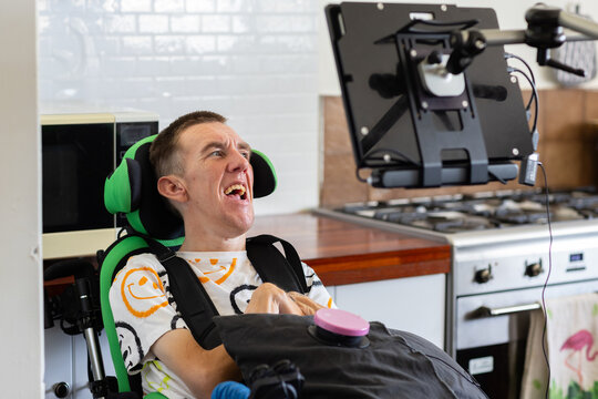Young man with disability on his wheelchair smiling at accessibility screen technology