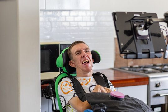 Young man with disability on his wheelchair using an assistive communication device