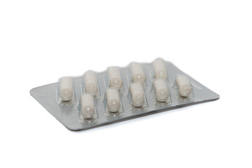 White capsules or pills in a silver blister pack. Close-up.