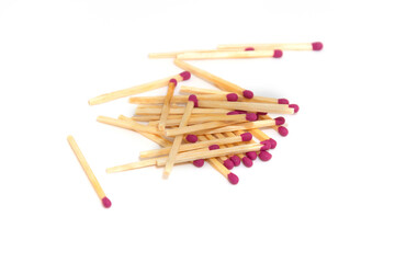 Wooden matches with red tips scattered on a white background.
