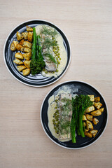 Two plates of barramundi and vegetable meal.