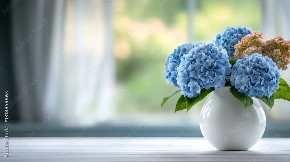 Poster vase of blue flowers sits on a table by a window. the flowers are in a white vase and are arranged i