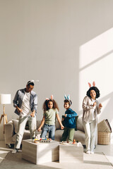 Happy family wearing bunny ears dancing and celebrating Easter at home
