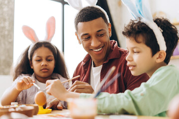 Happy, handsome African American man Family painting easter eggs wearing bunny ears