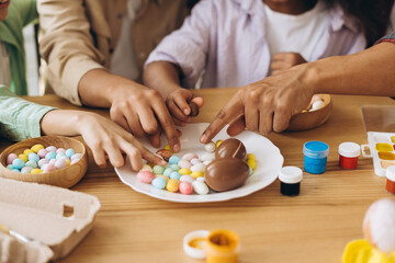 Family painting easter eggs and enjoying chocolate treats during easter celebration