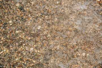 multi-colored stones under water on the sea, river. Natural background of stones, glare on the water
