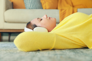 Young happy woman lying on the floor listening to music at home