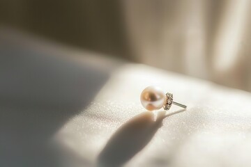 Obraz premium Elegant Pearl Earring with Reflective Light on Soft Fabric Background