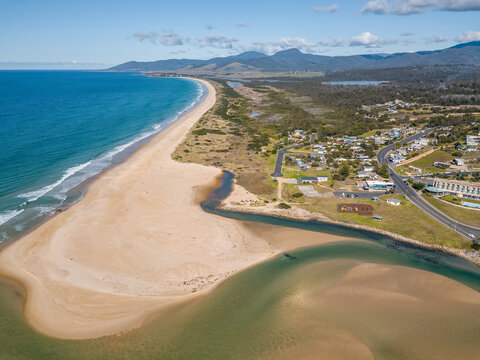 Aerial view of a river flowing past a coastal town and out into the ocean