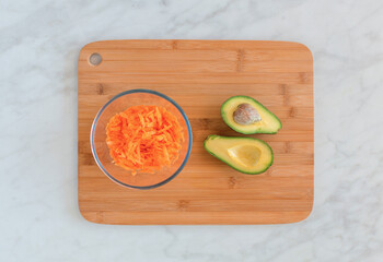 Top down of carrot and avocado ingredients on chopping block