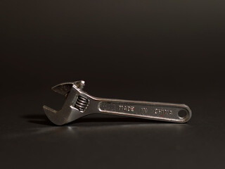 adjustable wrench on black background