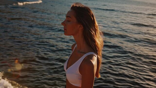 Serene Woman Standing by the Water's Edge at Sunset