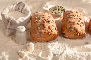 Fresh seed-covered buns placed on a lightly floured surface.