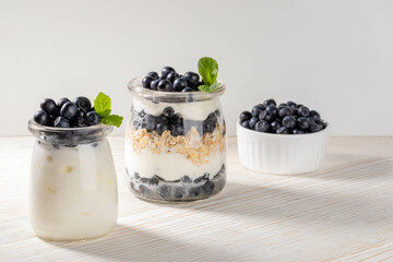 Yogurt with granola and forest blueberry and mint in glass jars Blueberry in bowl Healthy breakfast