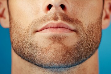 Obraz premium Close up of a mans lower face with well groomed stubble and strong jawline in a high resolution portrait with a blue gradient background