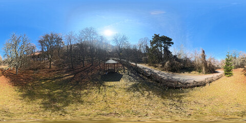 A breathtaking 360 HDRI panorama of an outdoor woods scene in spring, featuring lush green trees, vibrant foliage, and soft natural light filtering through the canopy. 