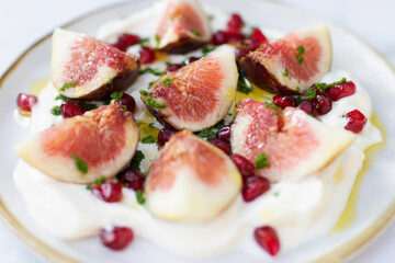 Delicious fig healthy garnished with pomegranate on greek yogurt and virgin olive oil.
