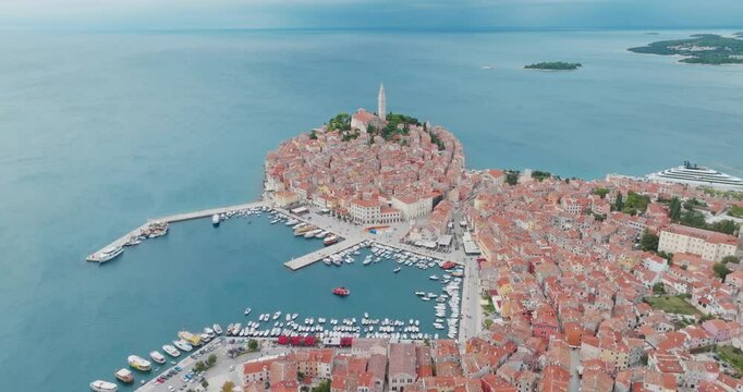 It offers a unique view from a diving drone over the historic peninsula of Rovinj, revealing the harbour and surrounding islands as it descends towards the iconic church tower.