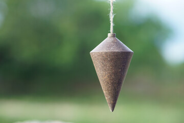Old plumb bob, plummet or conical iron hanging with rope for measurement level, use for determining perpendicularity . Concept, work tool for construction and carpentry. 