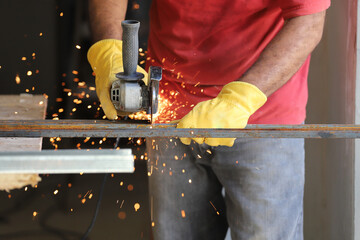 Industrial worker cutting iron with a grinder that produces sparks. Blacksmith in his workshop	
