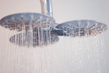 A high-resolution close-up of a modern triple-head shower system with water cascading down,...