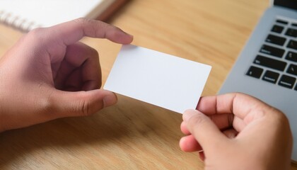 Obraz premium person holding blank business card near a laptop, ready for your custom message.