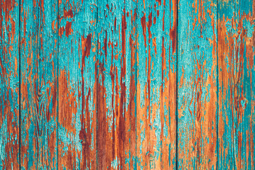 A close-up of aged wooden planks with peeling turquoise paint, revealing the warm brown wood beneath. The detailed texture and vibrant contrast create a rustic, weathered aesthetic