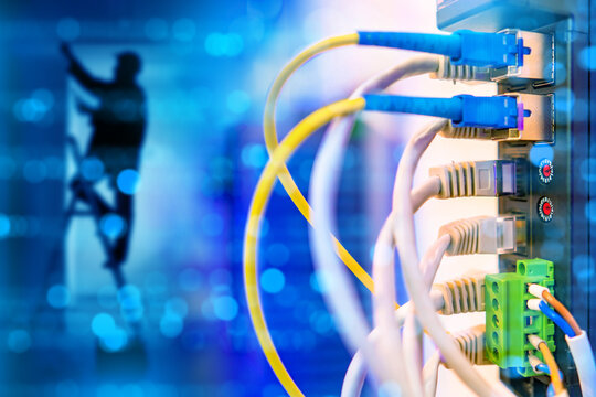 Network hardware. Man is electrician. Network switch with wires. Internet equipment inside building. Concept for setting up telecommunications equipment. Switch with fiber optic wires.