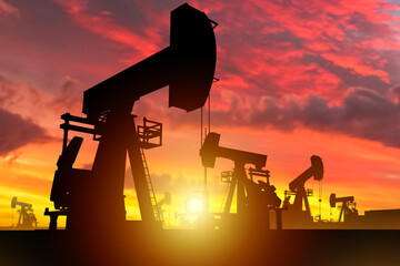 Oil birthplace at sunset. Silhouettes of oil pumps under evening sky. Industrial landscape....