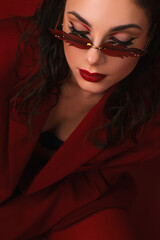 Young Woman In Red Suit With Red Lips And Sunglasses Posing On The Red Background