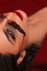 Young Woman In Red Suit With Red Lips And Sunglasses Posing On The Red Background