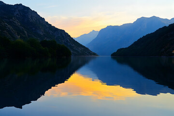 A warm sunset reflecting in the mirror-like surface of a tranquil lake