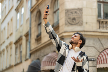 Young male tourist in casual and eyeglasses trying to catch a communication signal and Internet on...