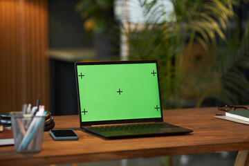 Close-up of laptop with green interface on workplace of manager in office