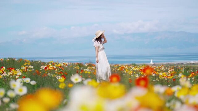 Young woman traveler relaxing and enjoying at beautiful blooming poppy flower fields at sayram lake in Xinjiang, China