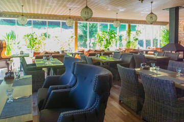 Stylish restaurant, Elegant interior with large windows, blue chairs, and wicker seating. Inviting...