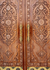 large carved wooden gates in oriental style with large copper handles