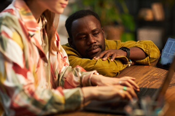 African American man watching for the work of programmer at table in office