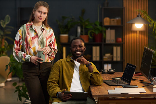 Portrait of team of programmers smiling at camera while working with security codes in eco office