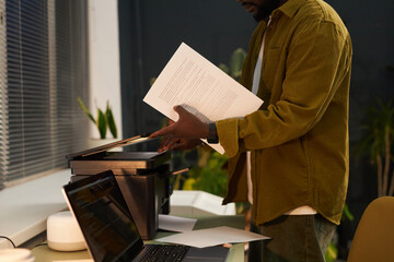 African American businessman using printer to make copy of document in office