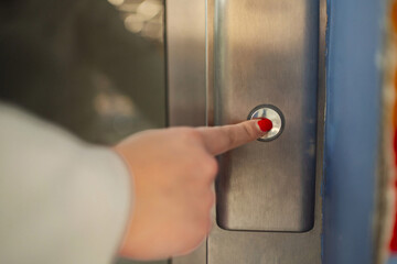 Naklejka premium Hand pressing an elevator button in a modern building hallway