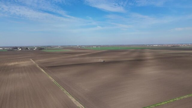 Aerial View of Farmland with Tractor Preparing Field for Planting on a Sunny Day


