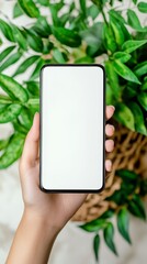 Blank smartphone screen held by hand with green leaves in background for mobile moc kup